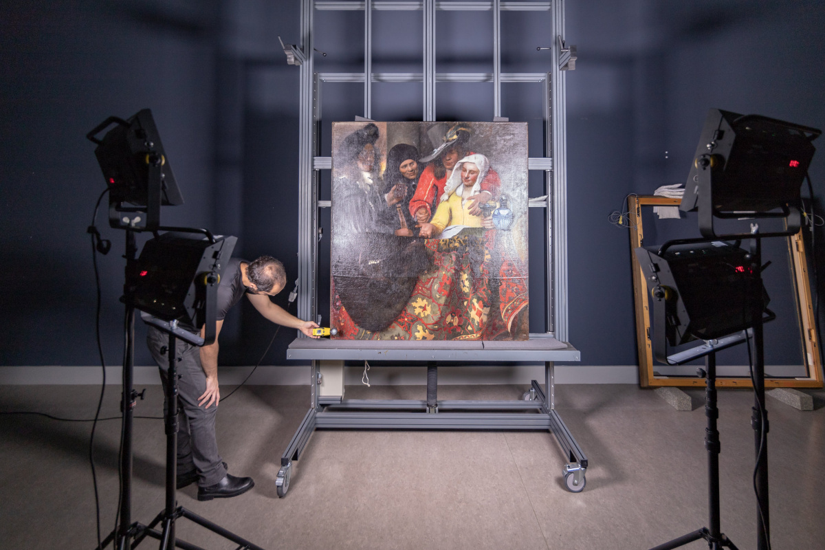 A photographer takes a high-resolution photo of "The Procuress," a painting by Vermeer. All authenti A photographer takes a high-resolution photo of "The Procuress," a painting by Vermeer. All authenti