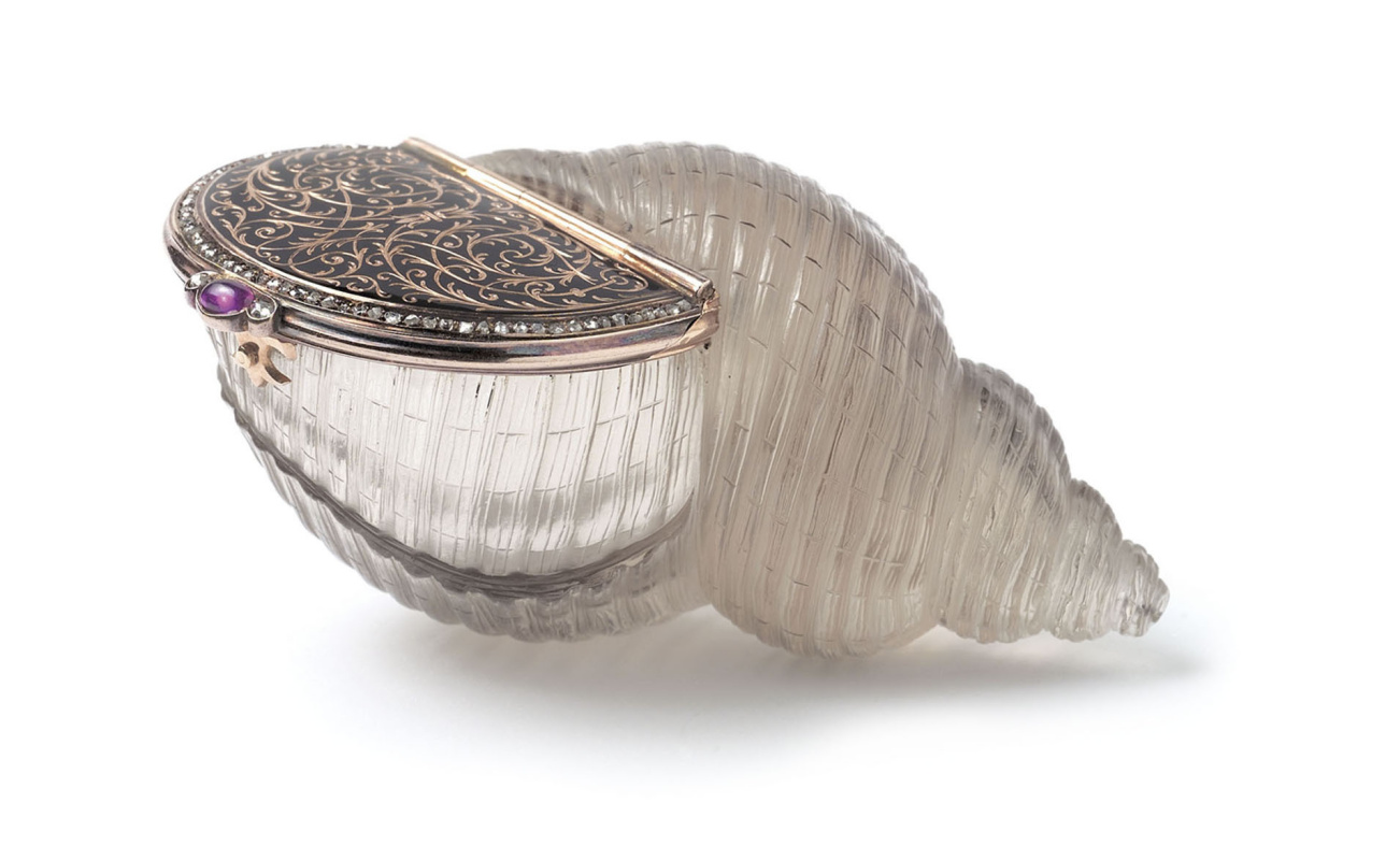 The shell-shaped enamel bonbonniere cut from solid topaz with hinged lid. The lid is inlaid with gol